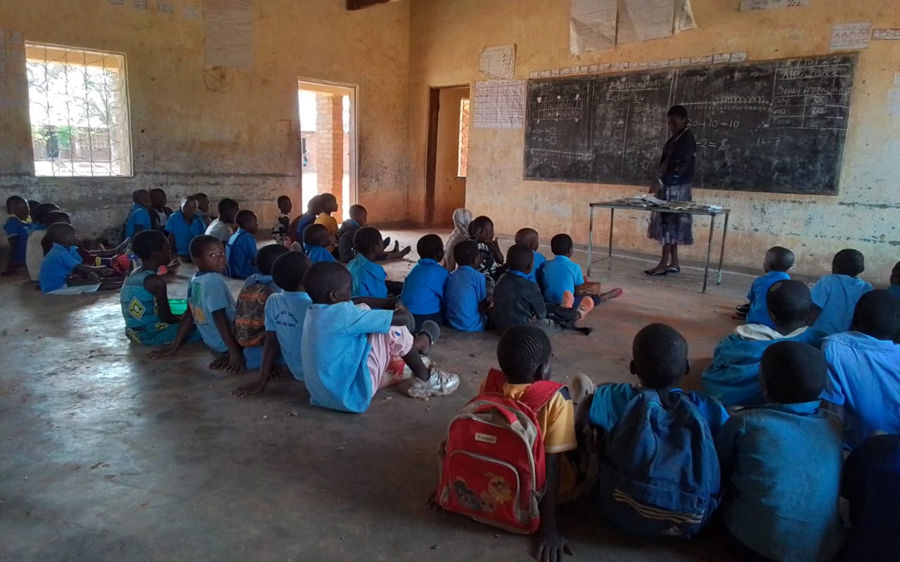 Learners with school bags attending a lesson led by their teacher