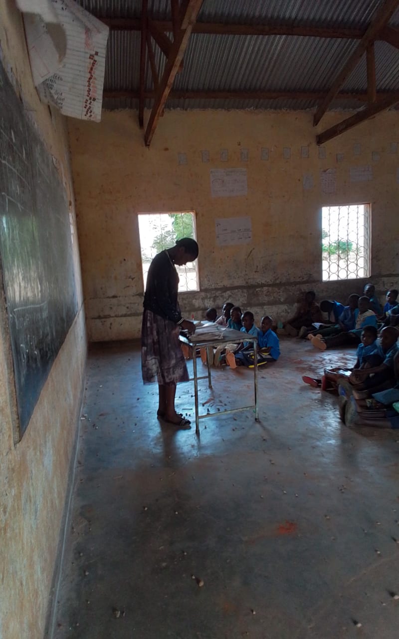 A Chipata Primary School teacher preparing materials beside the classroom board